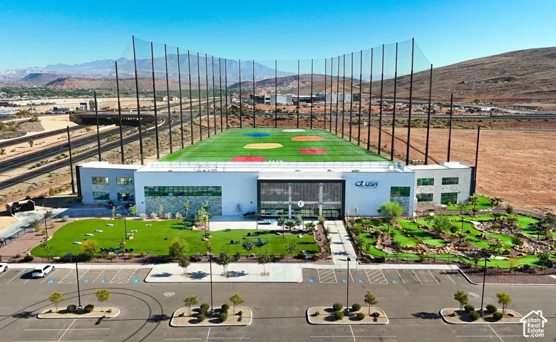 Expansive golf facility featuring a multi-story driving range with high netting, a putting green, and a miniature golf course