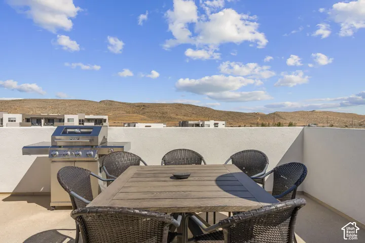 Rooftop patio featuring a built-in stainless steel grill, a neutral-toned privacy wall, and desert landscape beyond