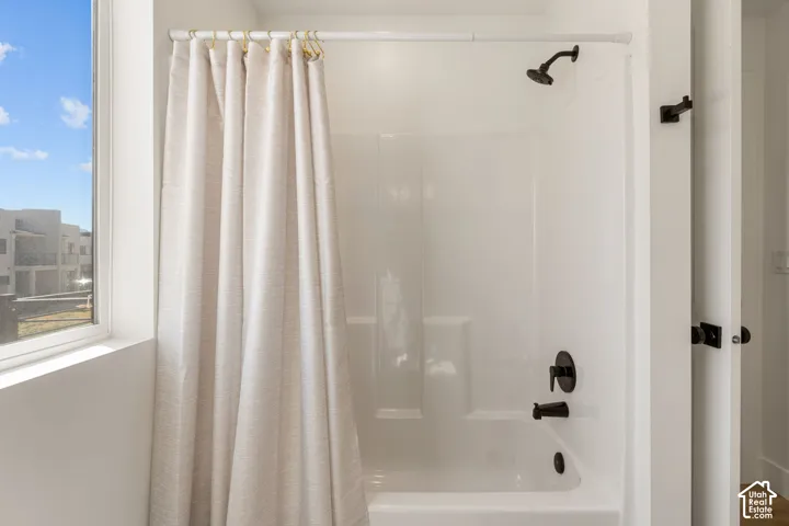 Bathroom featuring a white shower-over-tub unit with matte black fixtures