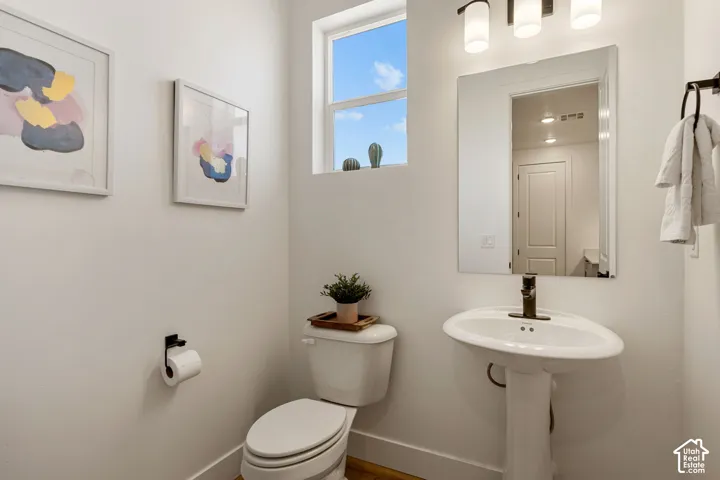 Pedestal sink with a bronze-finish faucet, mirror, and three-light vanity fixture
