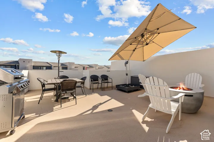Rooftop deck featuring a built-in outdoor grill, a fire pit, and ample open-air space