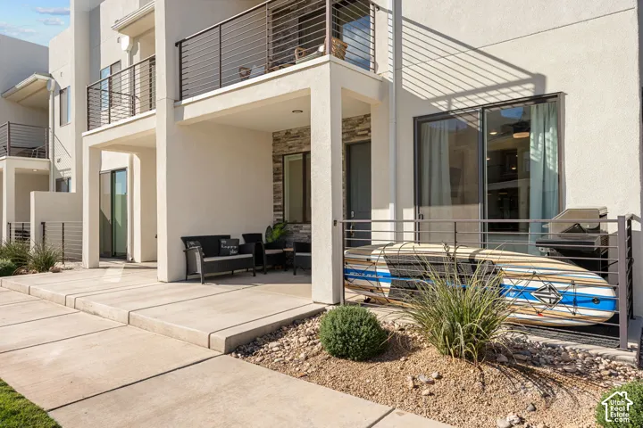 Ground-level patio with concrete pavers and a covered outdoor seating area featuring a stone accent wall