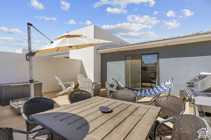 Rooftop patio featuring light-toned concrete flooring, partial privacy walls, and a sliding glass door entry