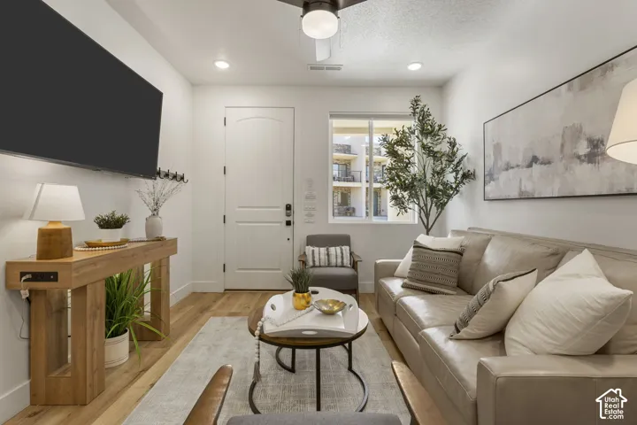 Light-filled living area featuring wood-finish flooring, a contemporary ceiling fan, recessed lighting, and a window providing natural light