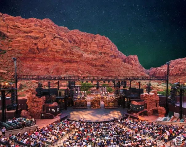 Outdoor amphitheater with tiered seating, stage, and complex set designs