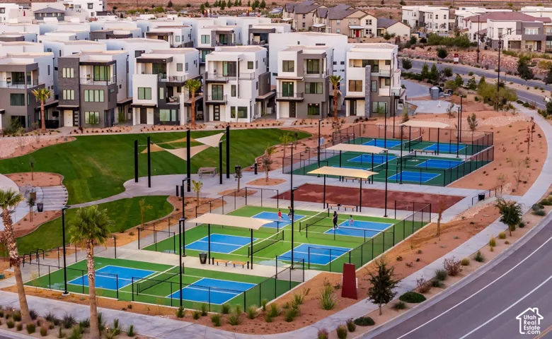Community amenities featuring multiple pickleball courts, expansive green space, shaded seating areas, and modern residential architecture