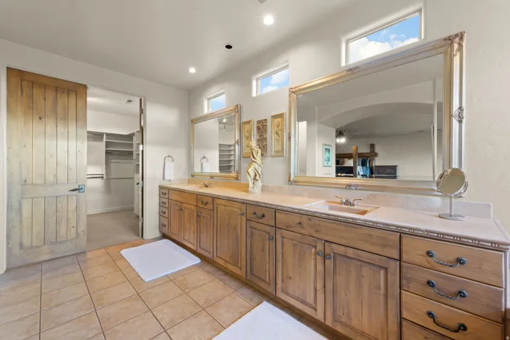 Spacious bathroom featuring an extended wood-finish vanity with dual sinks and ample storage cabinetry