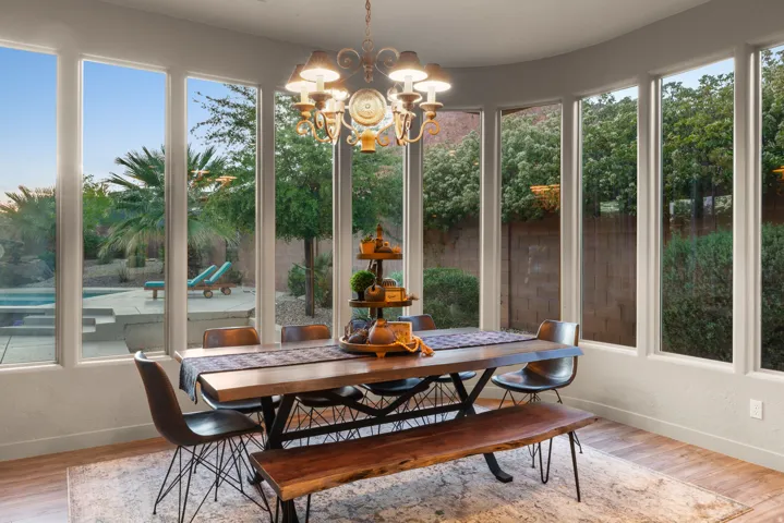 Dining area featuring a curved wall of floor-to-ceiling windows overlooking a backyard with a pool