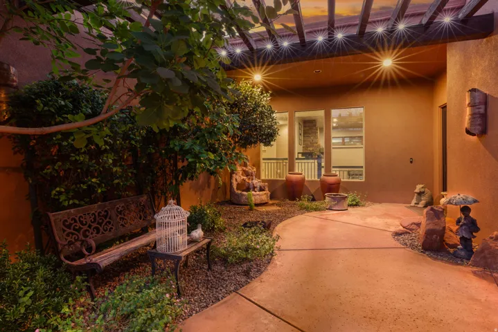 Curved concrete pathway leading to a stucco exterior with multiple windows and an entry door