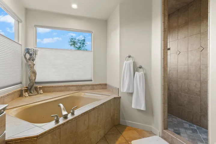 Garden soaking tub with tile surround, brushed nickel fixtures, and cellular shades