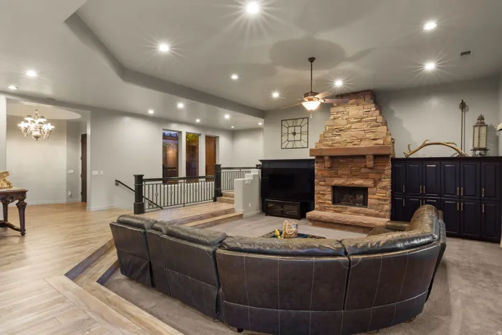 Sunken living area featuring a stone-clad fireplace with a wood mantel, recessed lighting, a ceiling fan, and built-in cabinetry