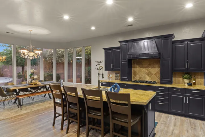 Kitchen featuring dark cabinetry, lighter granite countertops, a tiled backsplash, and recessed lighting