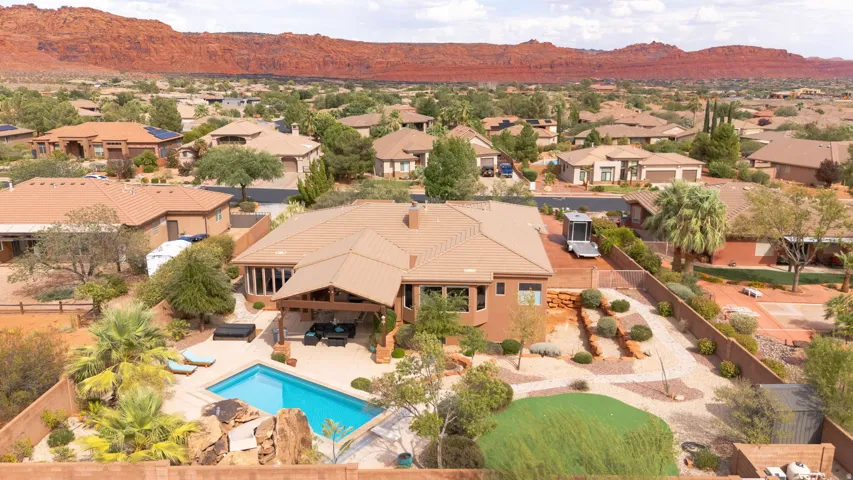 Exterior featuring a private pool, covered patio, desert landscaping, and a red rock backdrop