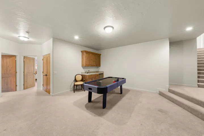 Carpeted open area featuring a built-in wet bar with wood cabinetry and a light-toned countertop