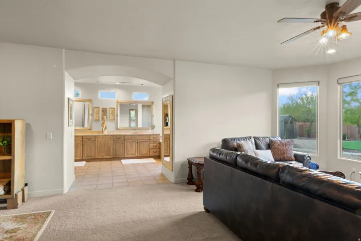 Arched entryway opening to a spacious bathroom with double vanities, multiple mirrors, and a tiled floor