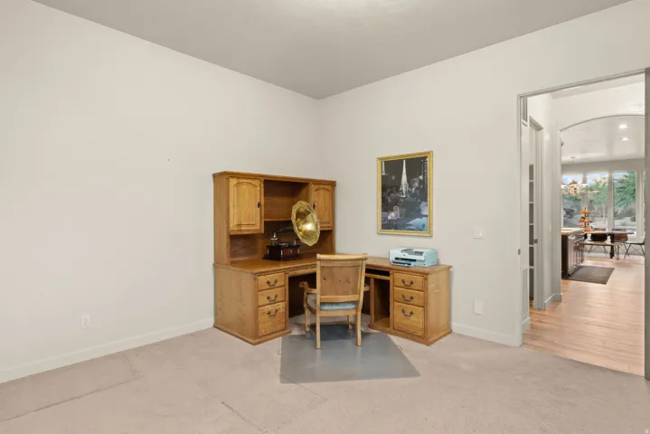 Carpeted room featuring light-toned walls and an arched doorway opening to a wood-finish floor