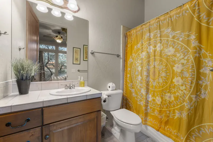 Bathroom featuring a wood-finish vanity with a tiled countertop, undermount sink, and chrome fixtures