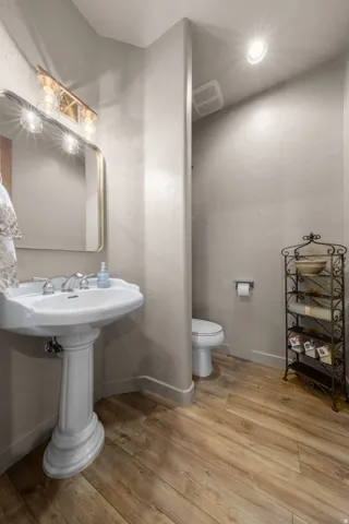 Pedestal sink with polished chrome fixtures and an arched mirror with a gold-tone frame