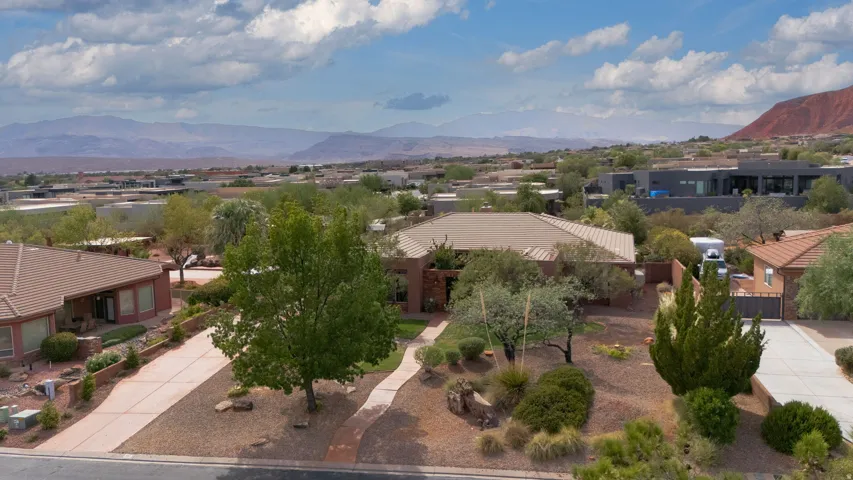 Single-story residence with a tiled roof, mature landscaping, and a curvilinear paved walkway