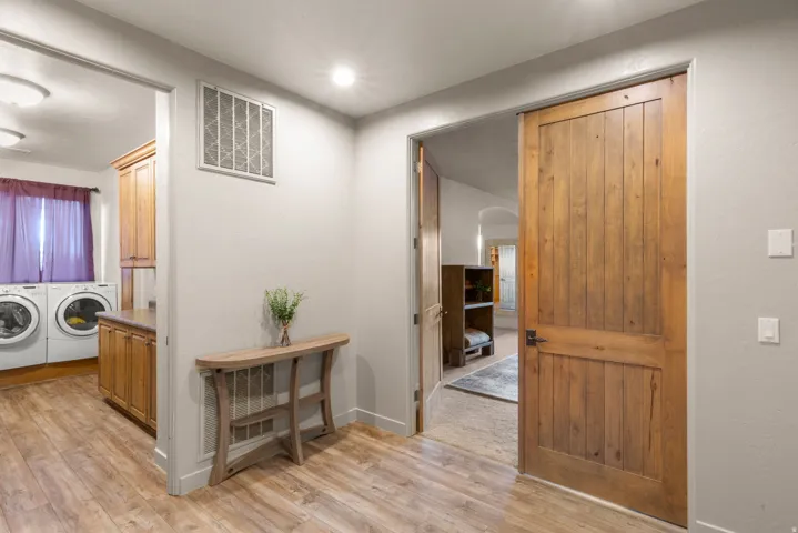 Laundry area featuring wood-finish flooring, recessed lighting, and built-in cabinetry with counter space