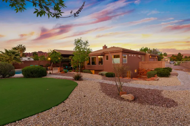 Expansive backyard featuring a putting green, a swimming pool, and desert landscaping with gravel and mature shrubs