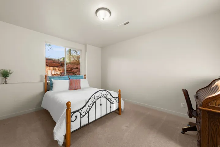 Carpeted room featuring a window with an exterior stone wall, a ceiling-mounted light fixture, and neutral-toned walls