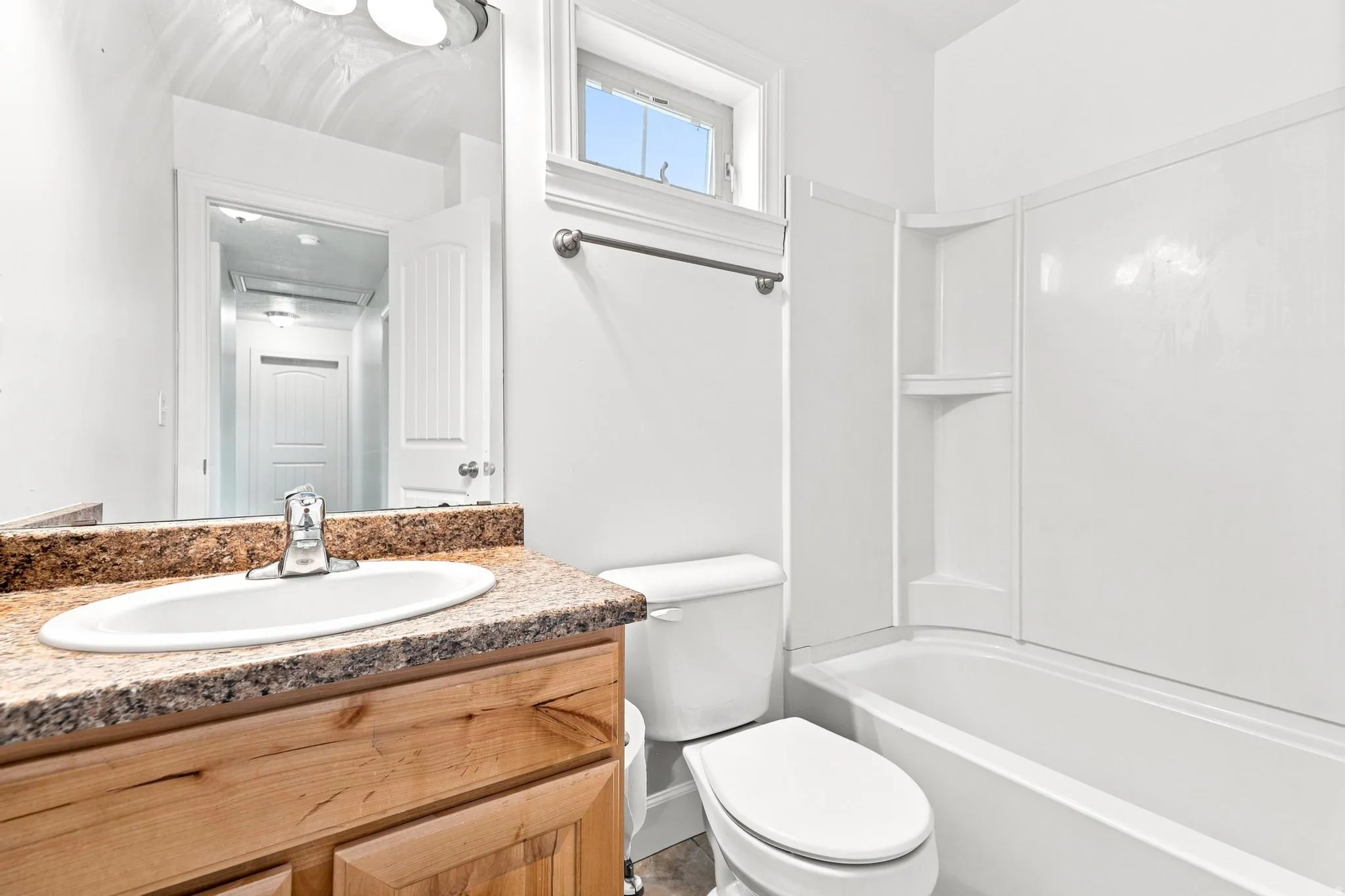 Bathroom featuring a wood-finish vanity with an integrated sink and a speckled countertop