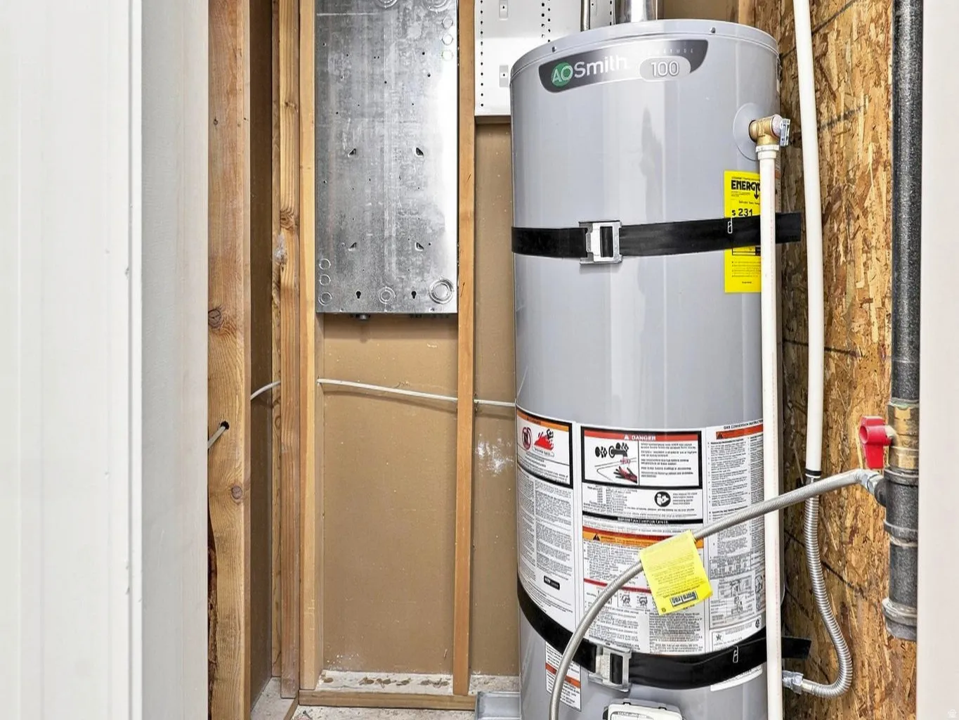 Water heater system with an expansion tank, integrated piping, and visible electrical wiring