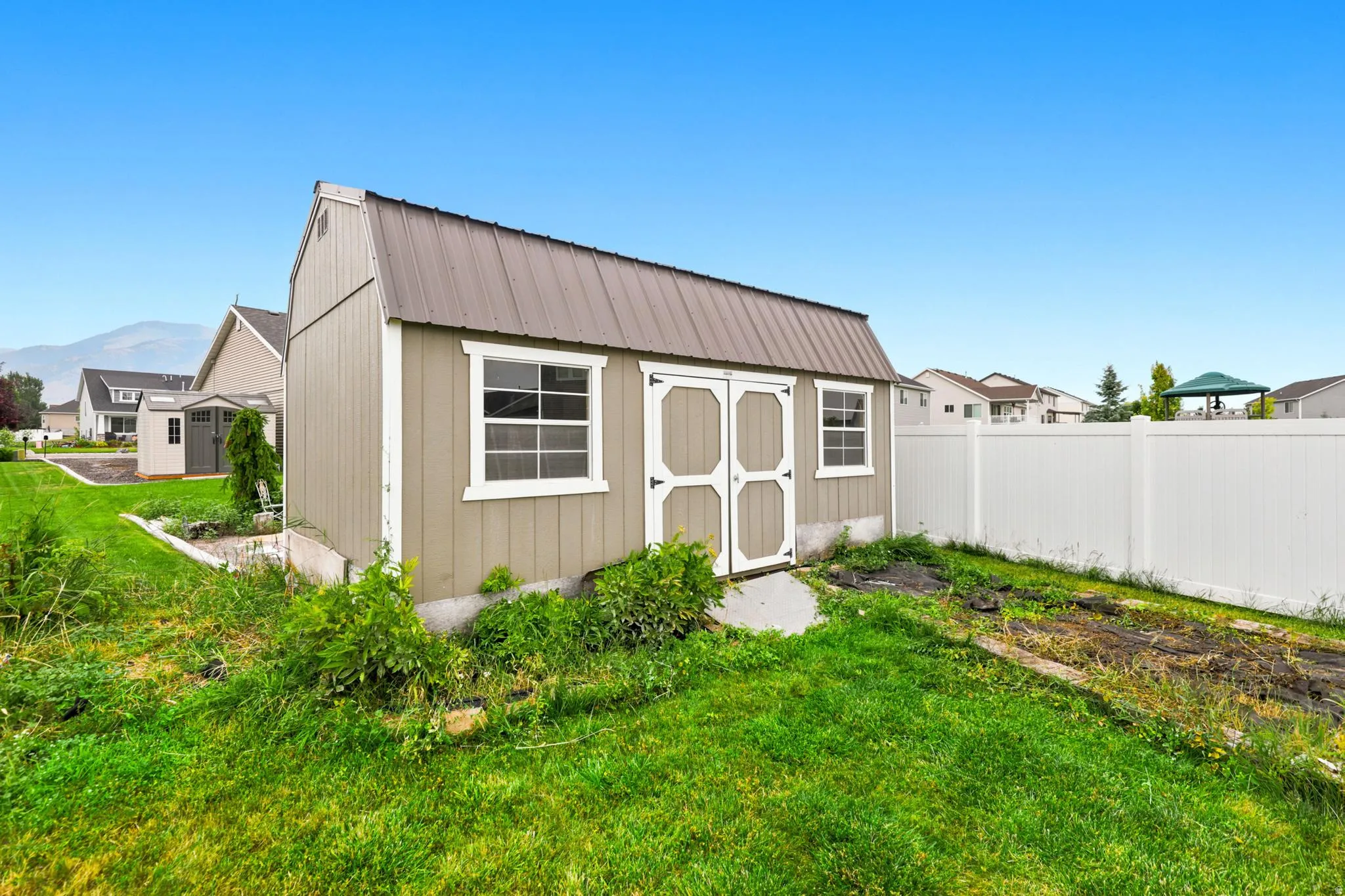 Freestanding shed with a metal roof, double entry doors, two windows, and exterior siding