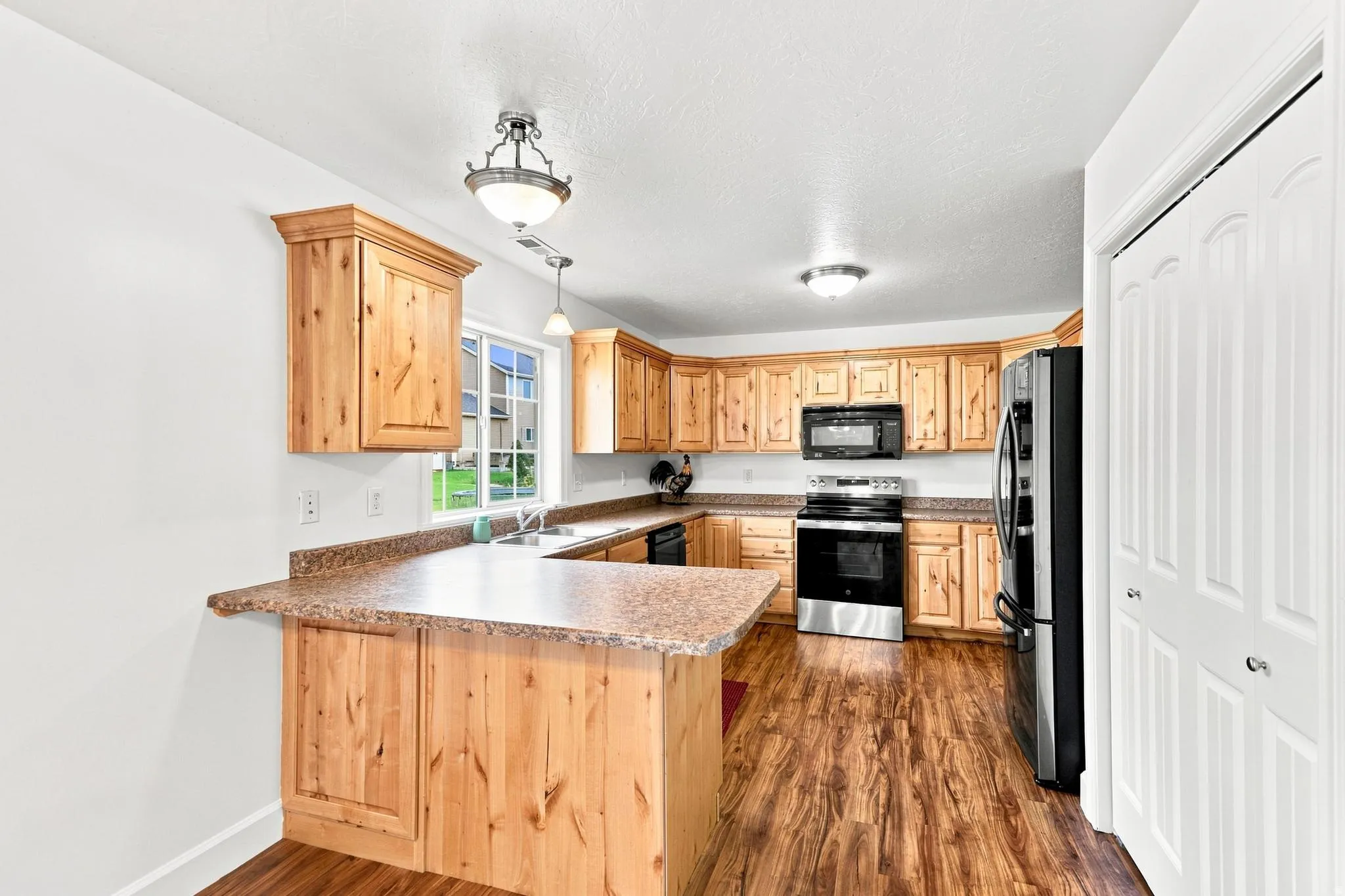 Kitchen featuring wood-finish cabinetry, speckled countertops, stainless steel appliances, and wood-finish flooring