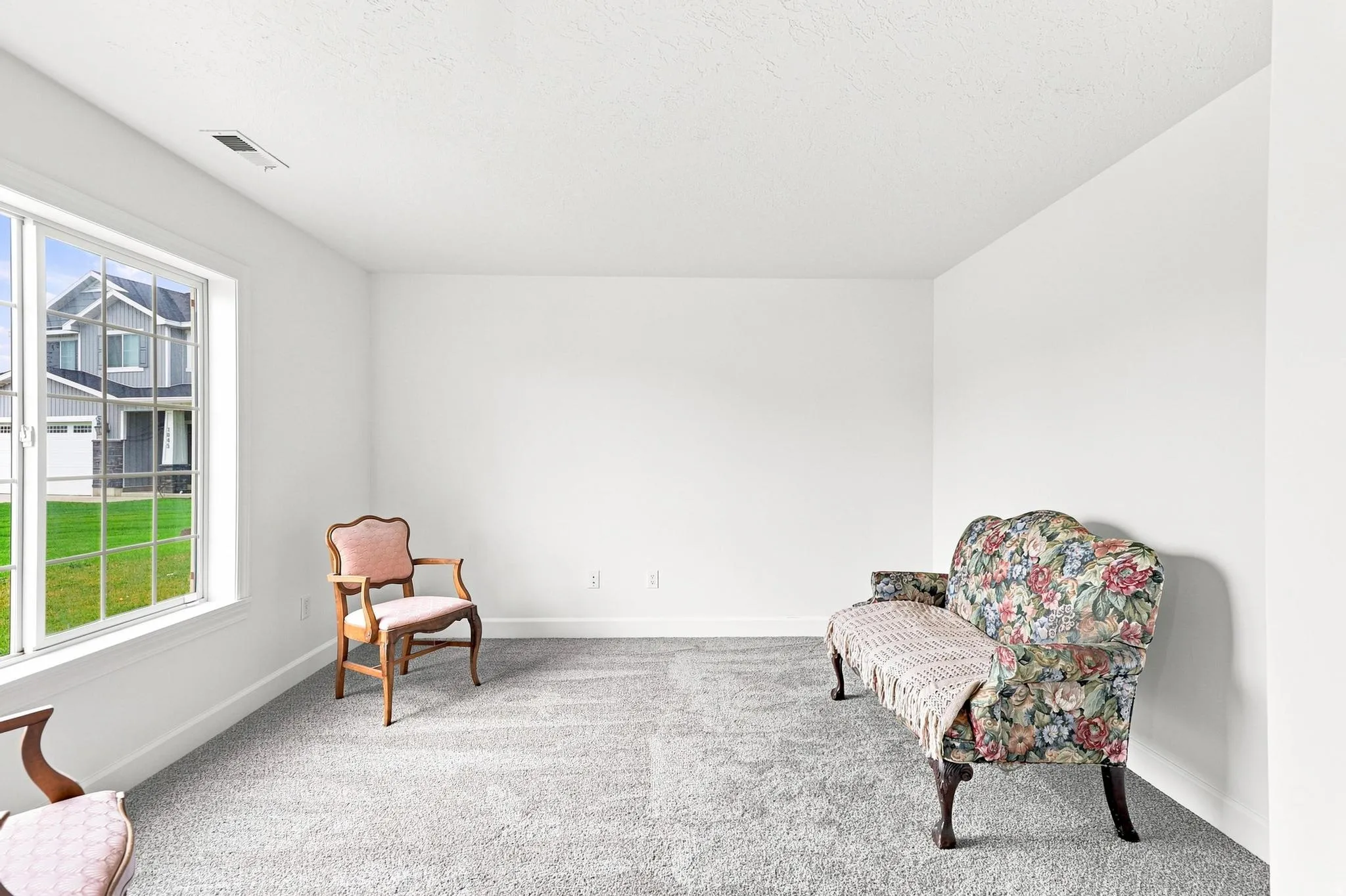 Spacious room with light gray carpeting and white walls