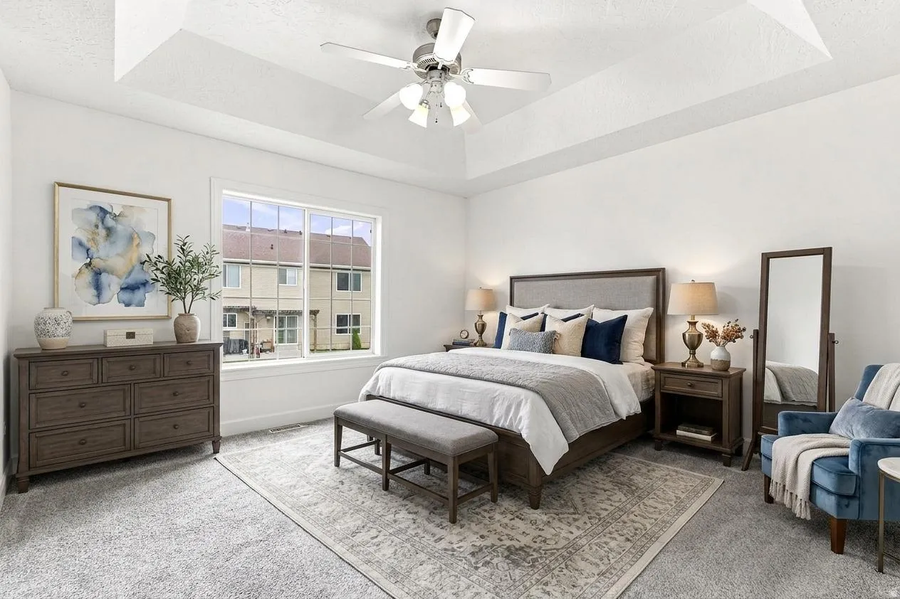 Spacious room featuring a tray ceiling, ceiling fan with integrated lighting, large window, and light-toned carpetingAI generated photo