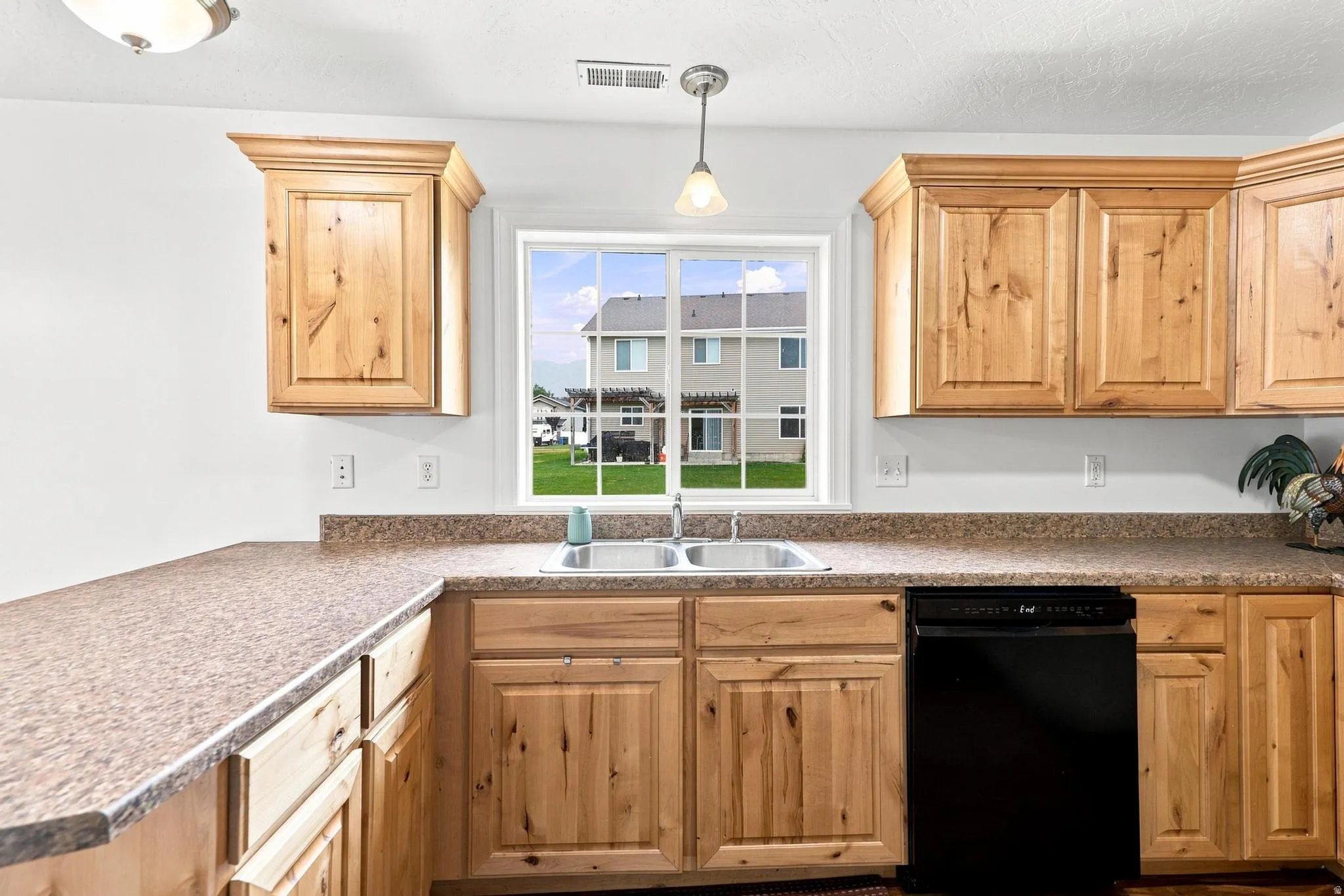 Kitchen featuring natural wood-finish cabinetry, speckled countertops, and a double basin stainless steel sink