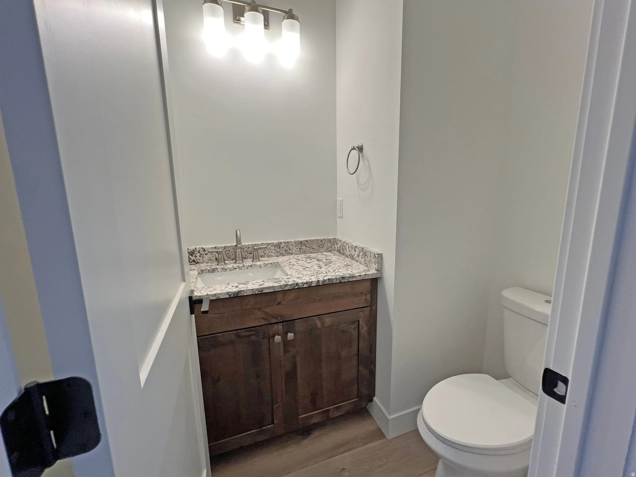 Powder room featuring a wood-finish vanity with a granite-style countertop and an undermount sink