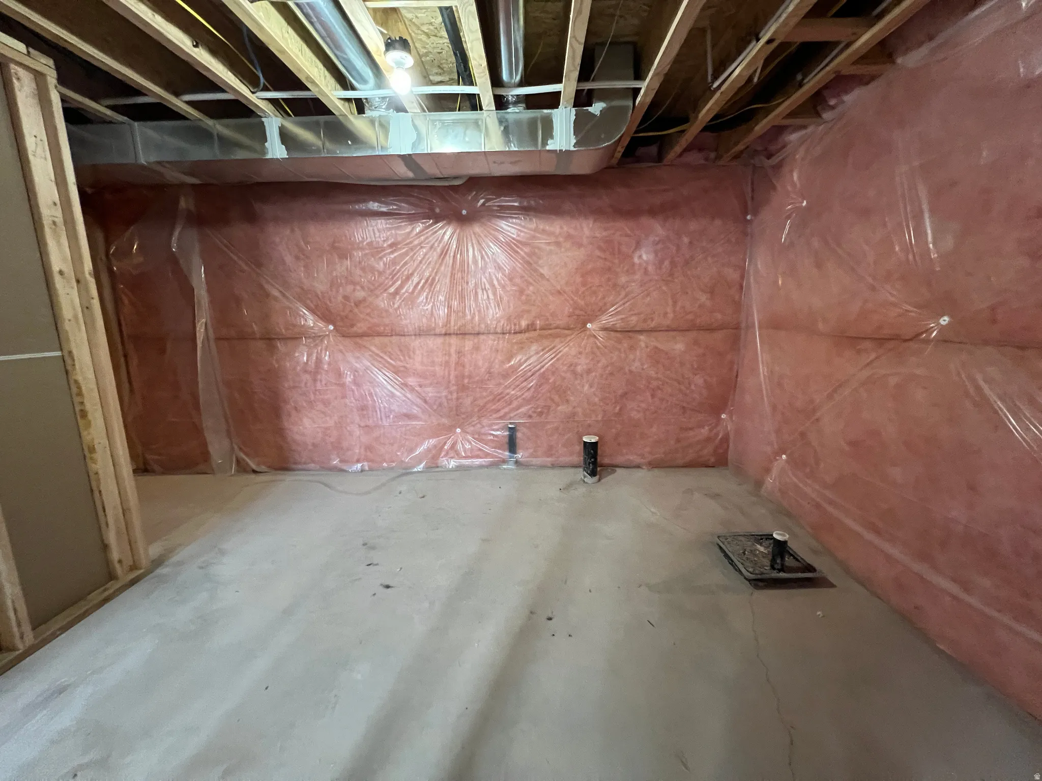 Unfinished basement featuring exposed wood joists, insulated walls, concrete flooring, and visible plumbing rough-ins