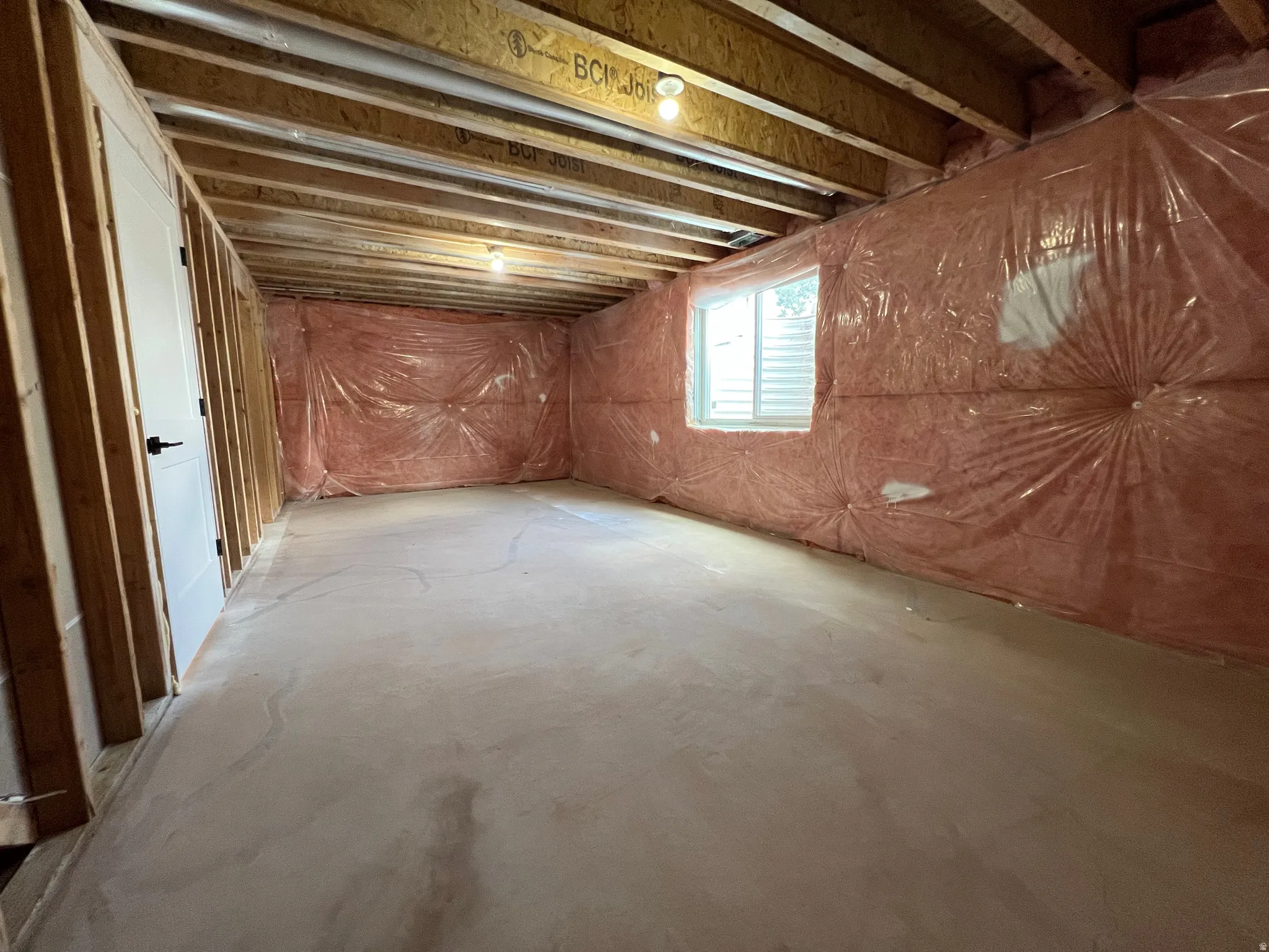 Unfinished basement offering exposed ceiling joists, framed wall partitions, and a single window with blinds