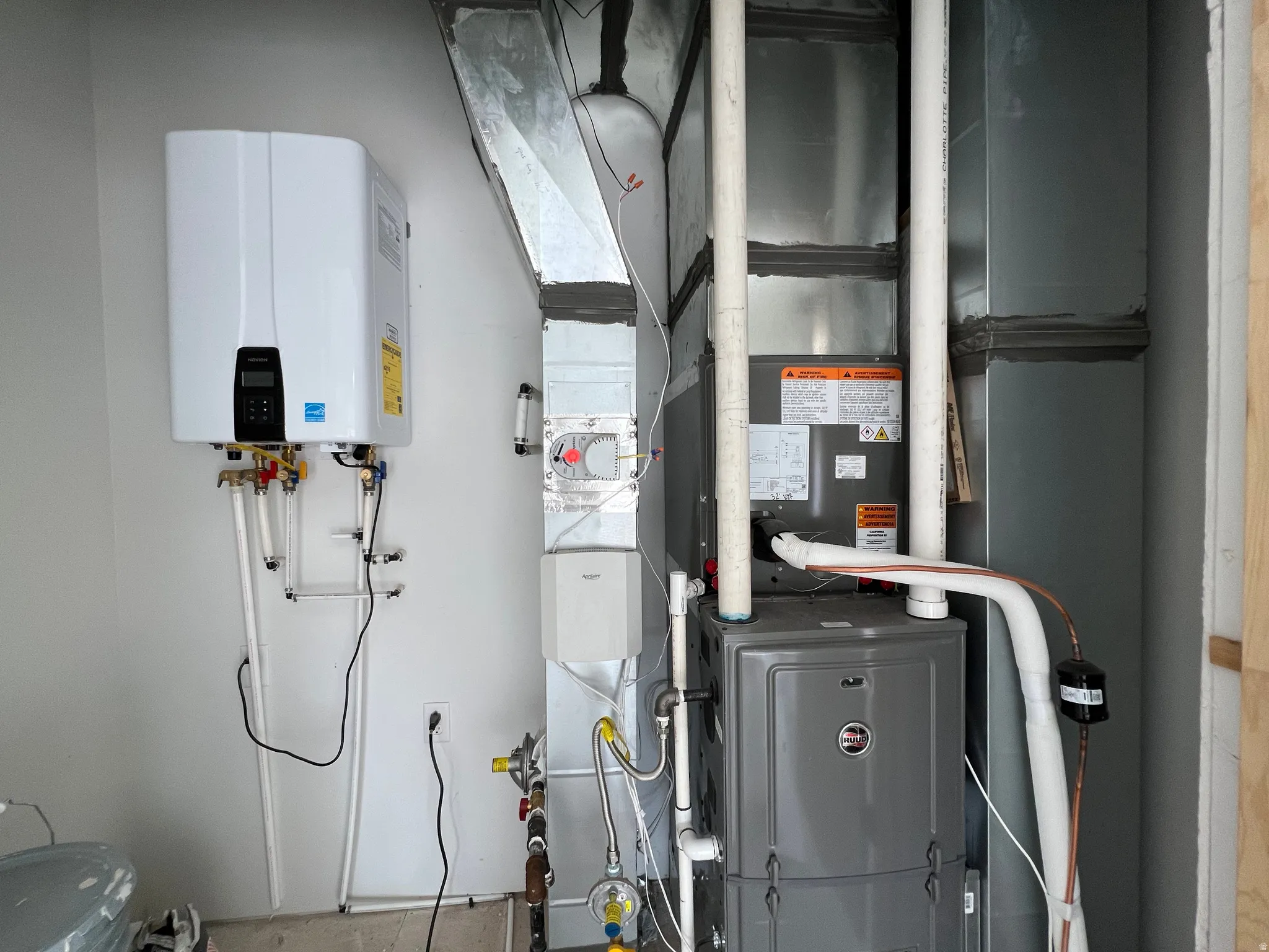 Wall-mounted tankless water heater, alongside a modern HVAC furnace and extensive ductwork
