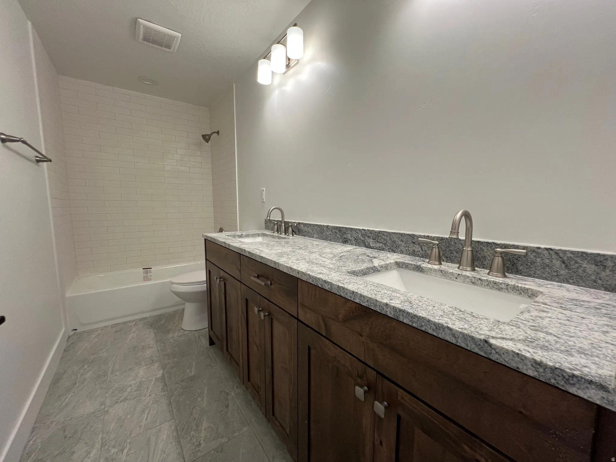 Bathroom featuring a dual vanity with a granite countertop, undermount sinks, and brushed nickel fixtures