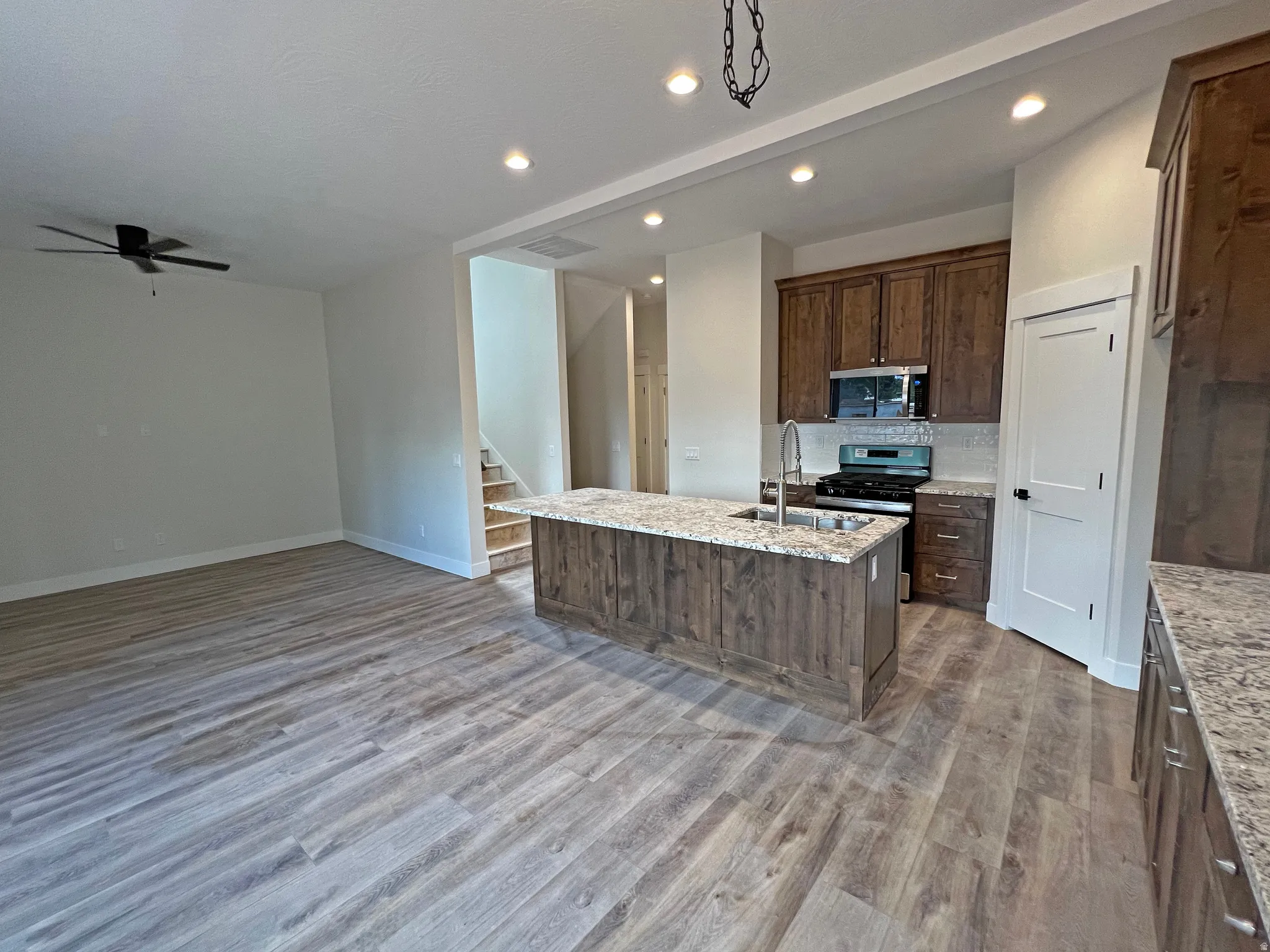 Open-concept living space featuring wood-finish flooring, recessed lighting, and a ceiling fan