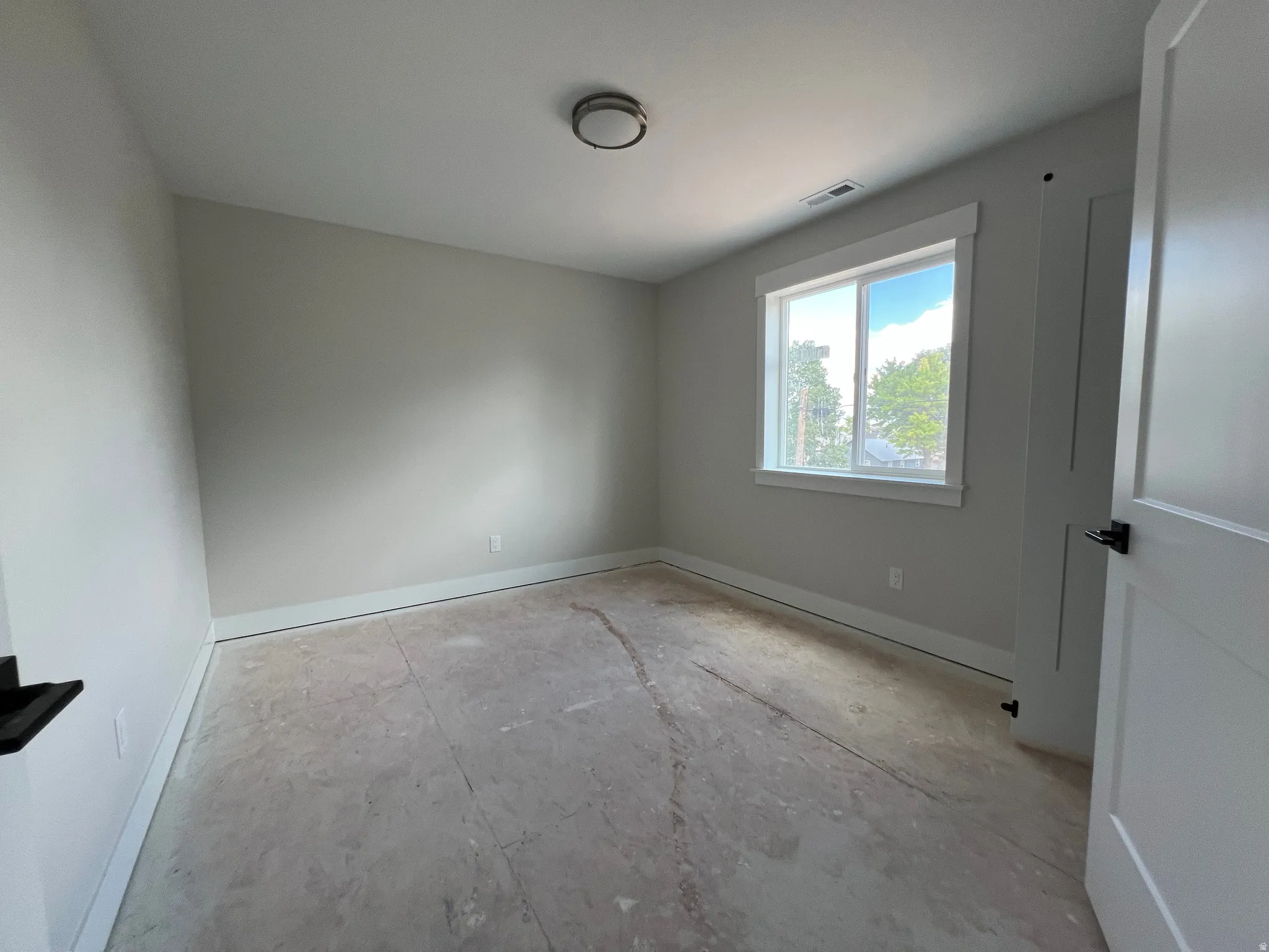 Bright interior space featuring a double-pane window, white trim throughout, and a flush-mount ceiling light