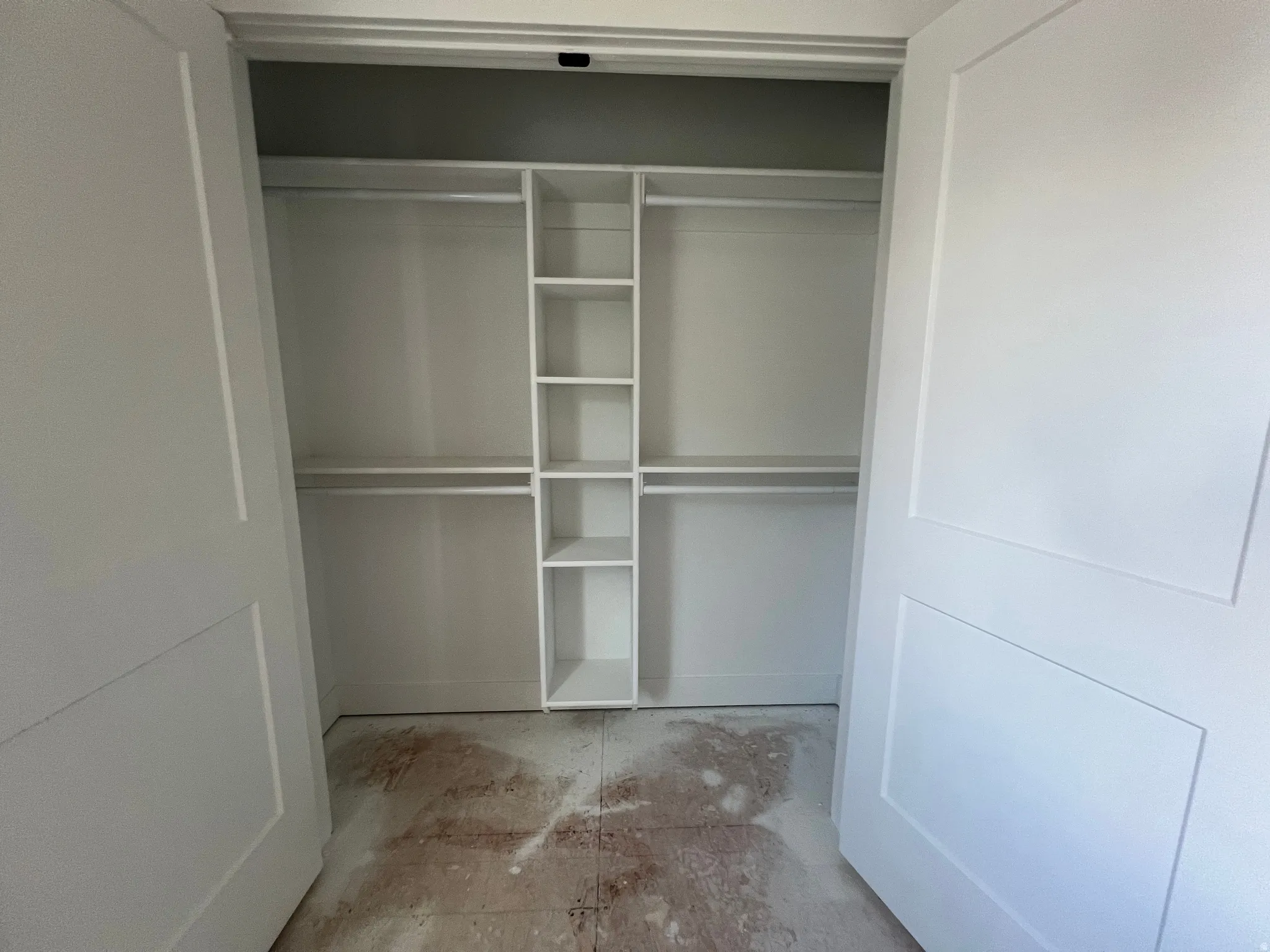 White closet system featuring integrated shelving and double hanging rods, framed by two-panel interior doors