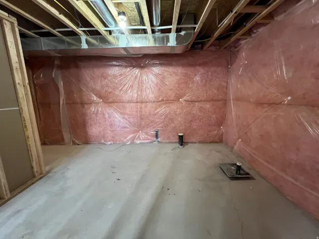 Unfinished basement featuring exposed wood joists, insulated walls, concrete flooring, and visible plumbing rough-ins