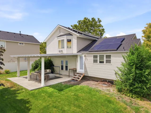 Rear exterior featuring a covered patio, solar panels, bay window, and siding