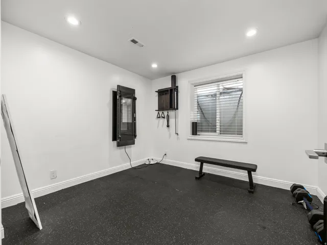 Dedicated room featuring recessed lighting, a built-in workout system, a window with horizontal blinds, and black rubber flooring