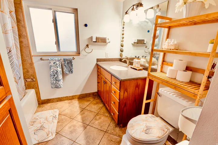 Bathroom featuring a wood-finish vanity with an integrated sink, a dark countertop, and a wall-mounted mirror