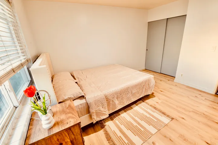 Bedroom featuring wood-finish flooring, a window with blinds, and light-colored walls