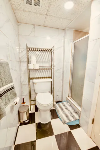 Full-height white marble-look wall tiling complemented by black and white checkerboard floor tiling
