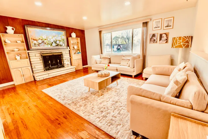 Living space featuring warm wood-finish flooring and a stone-clad fireplace