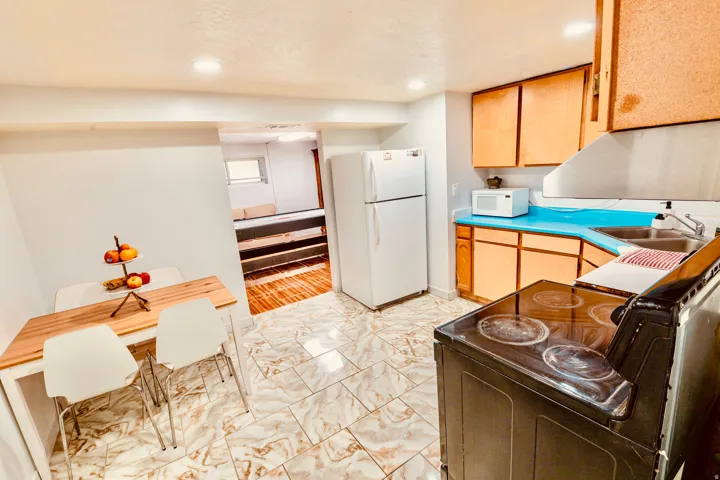 Kitchen area featuring light wood-finish cabinetry, bright blue countertops, and a white refrigerator