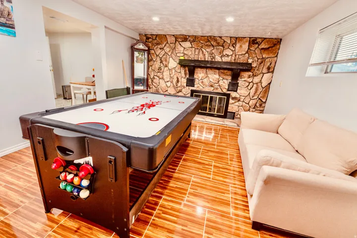 Recreation room featuring wood-finish flooring and a stone accent wall with a fireplace